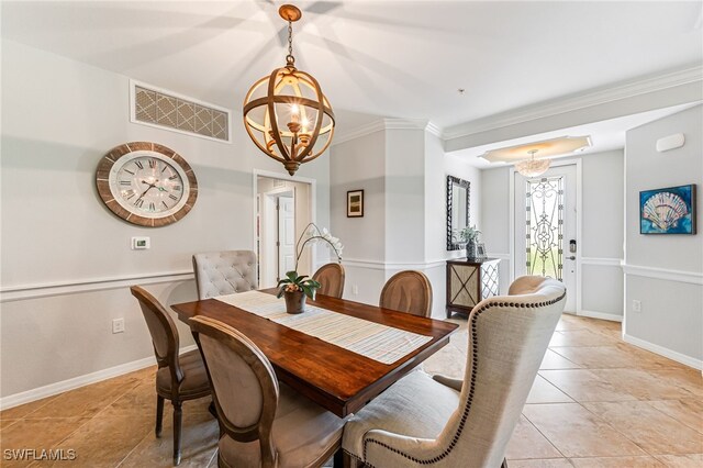 tiled dining area with crown molding and a notable chandelier