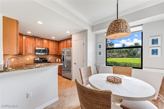 kitchen featuring light stone counters, light tile patterned flooring, decorative light fixtures, stainless steel appliances, and decorative backsplash