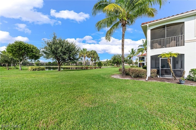 view of yard with a sunroom and a water view