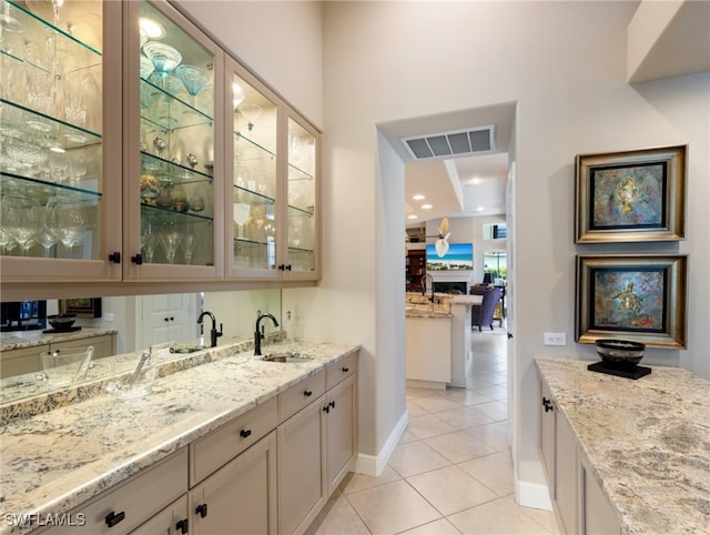 bar with lofted ceiling, light stone countertops, sink, and light tile patterned floors