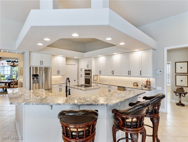 kitchen with light stone countertops, stainless steel appliances, white cabinets, a spacious island, and light tile patterned floors