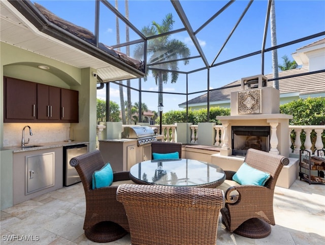 view of patio featuring an outdoor fireplace, sink, grilling area, area for grilling, and a lanai