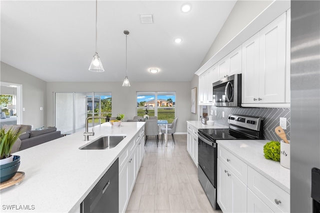 kitchen featuring a wealth of natural light, appliances with stainless steel finishes, hanging light fixtures, and sink