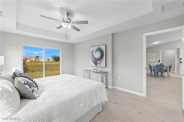 bedroom featuring ceiling fan, a tray ceiling, and access to exterior