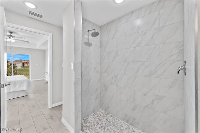 bathroom with a tile shower and ceiling fan