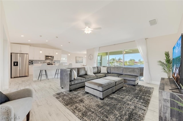 living room with ceiling fan, light hardwood / wood-style flooring, and vaulted ceiling