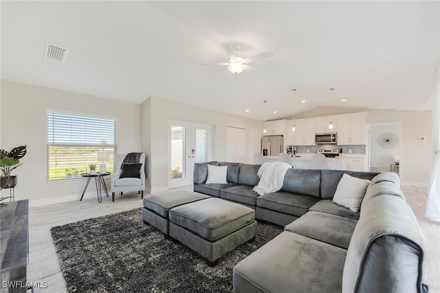 living room featuring ceiling fan, french doors, vaulted ceiling, and light wood-type flooring