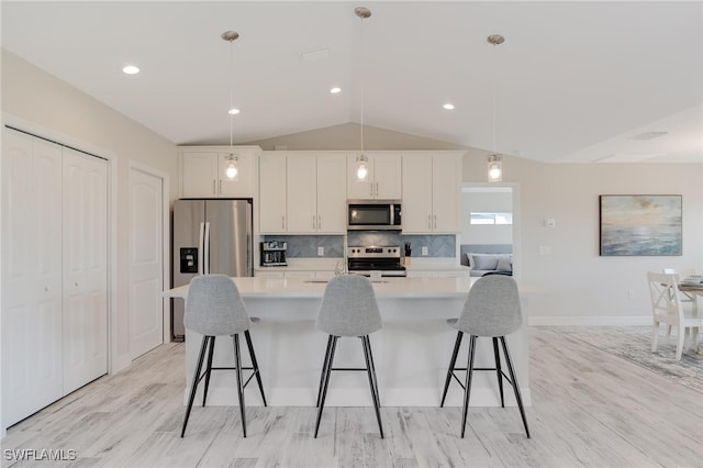 kitchen featuring lofted ceiling, white cabinets, light hardwood / wood-style flooring, decorative light fixtures, and stainless steel appliances