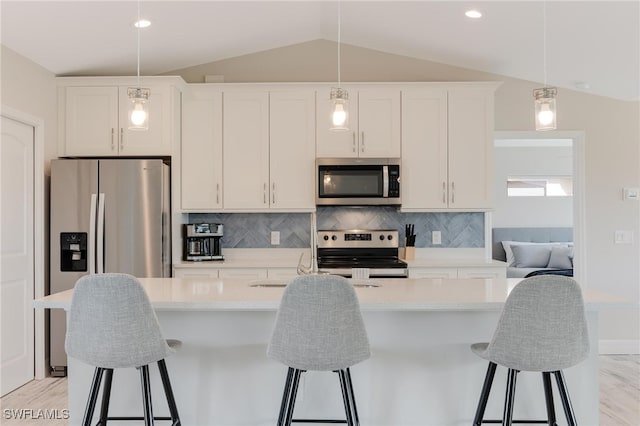 kitchen with white cabinetry, light hardwood / wood-style floors, lofted ceiling, a kitchen island with sink, and appliances with stainless steel finishes