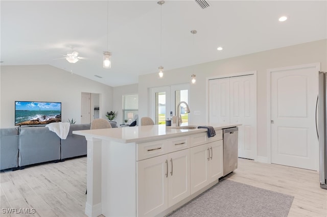 kitchen with ceiling fan, stainless steel appliances, an island with sink, pendant lighting, and white cabinets