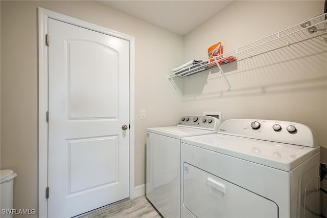 washroom with separate washer and dryer and light hardwood / wood-style flooring