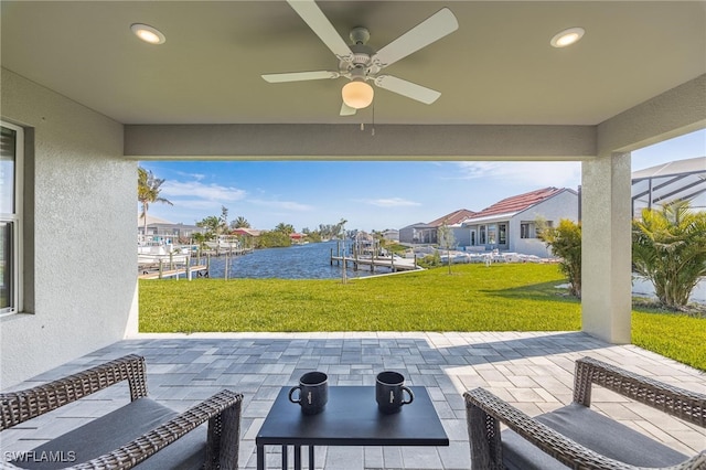 view of patio with ceiling fan, a water view, and a boat dock