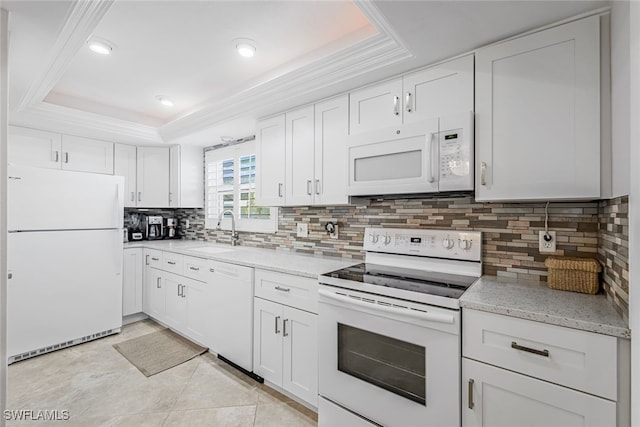 kitchen with white cabinetry, light stone counters, a raised ceiling, white appliances, and sink