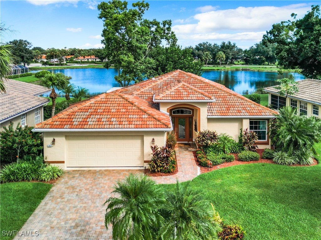 mediterranean / spanish-style home with a garage, a water view, and a front lawn