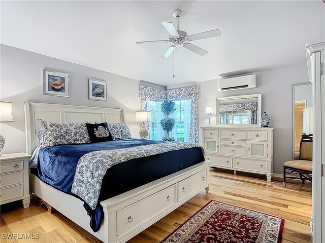 bedroom with light hardwood / wood-style flooring, ceiling fan, and a wall mounted AC