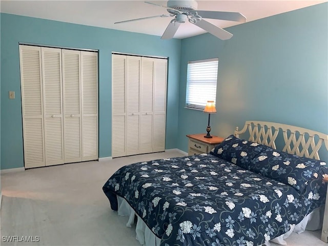 bedroom with light carpet, two closets, and ceiling fan