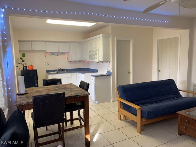 kitchen with ceiling fan, white cabinetry, sink, and light tile patterned floors