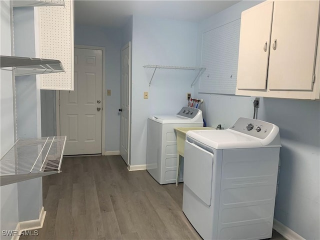 washroom with washer and dryer, light hardwood / wood-style floors, and cabinets