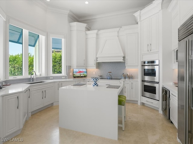 kitchen with white cabinets, beverage cooler, stainless steel appliances, sink, and a center island