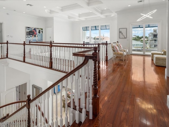 hallway featuring dark wood-type flooring, ornamental molding, a wealth of natural light, and beamed ceiling