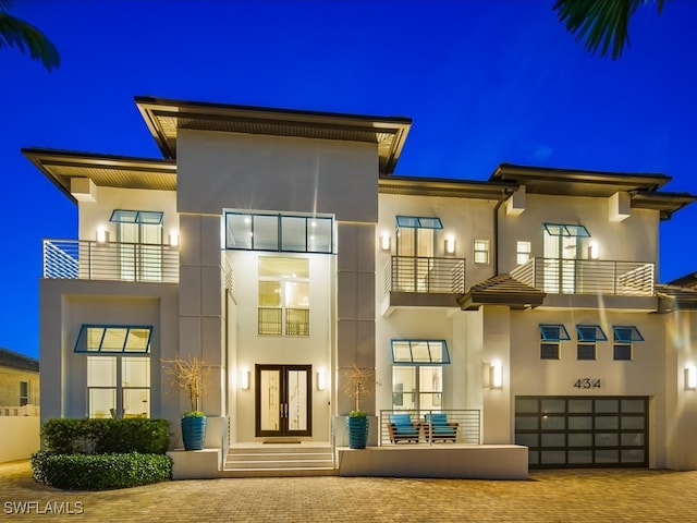 back house at twilight with a balcony and a garage