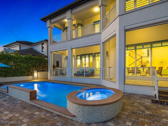 back of house with a patio, a pool with hot tub, and a balcony