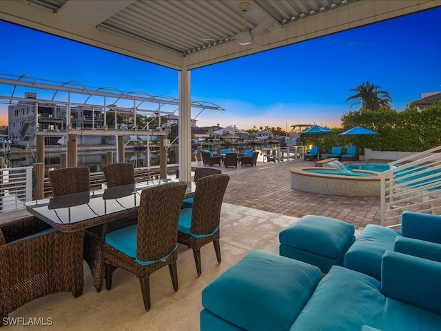 patio terrace at dusk with an in ground hot tub and a water view