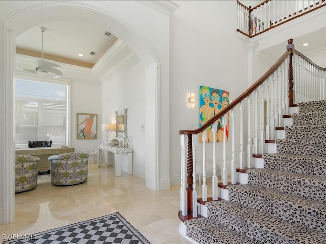 entryway featuring crown molding, a towering ceiling, and a raised ceiling