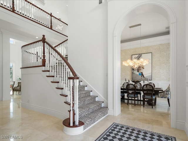 staircase featuring a towering ceiling and an inviting chandelier