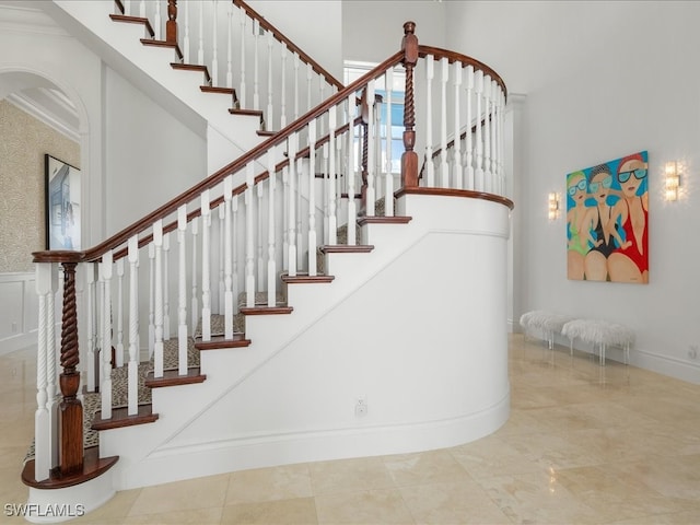 stairway with ornamental molding and a high ceiling