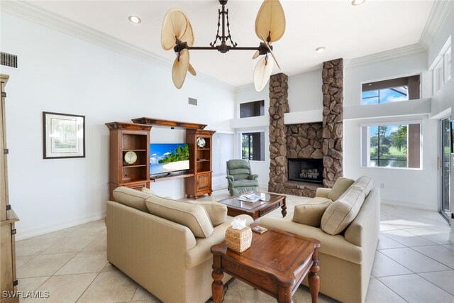 living room featuring a high ceiling, crown molding, light tile patterned floors, and a stone fireplace