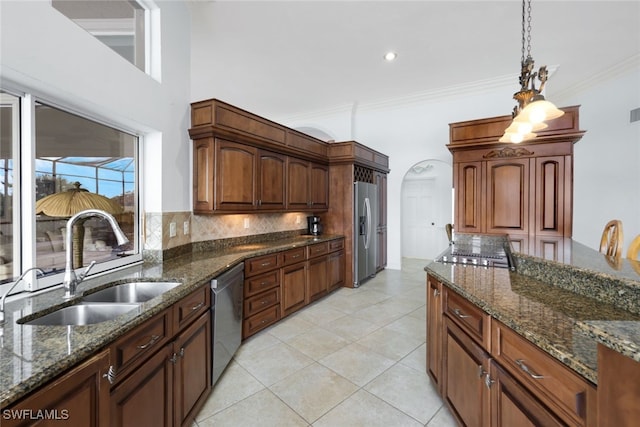 kitchen with ornamental molding, appliances with stainless steel finishes, decorative light fixtures, and dark stone counters