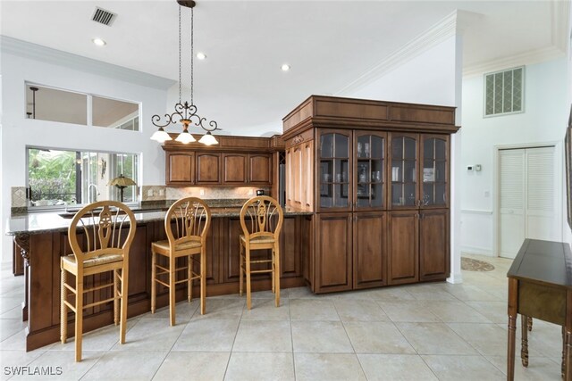 kitchen with a kitchen breakfast bar, backsplash, ornamental molding, and light tile patterned floors