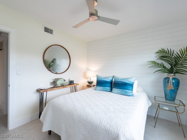 tiled bedroom featuring ceiling fan and wooden walls