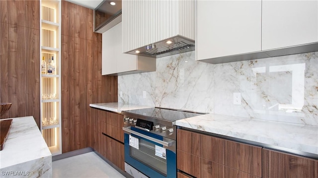 kitchen featuring custom exhaust hood, backsplash, electric range, white cabinets, and light stone counters