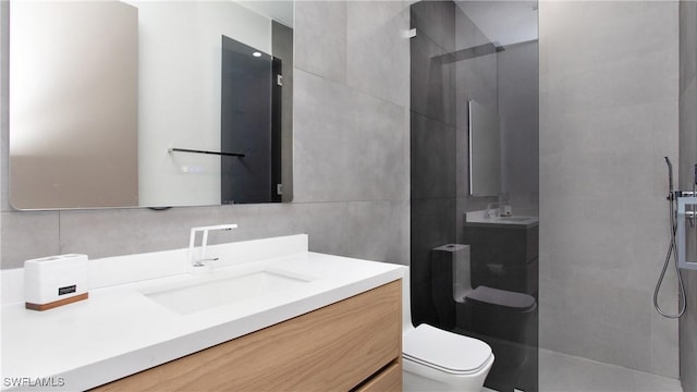 bathroom featuring toilet, vanity, tile walls, and a shower