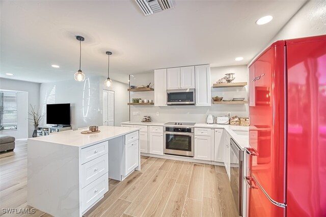 kitchen with pendant lighting, light hardwood / wood-style floors, a center island, white cabinets, and appliances with stainless steel finishes