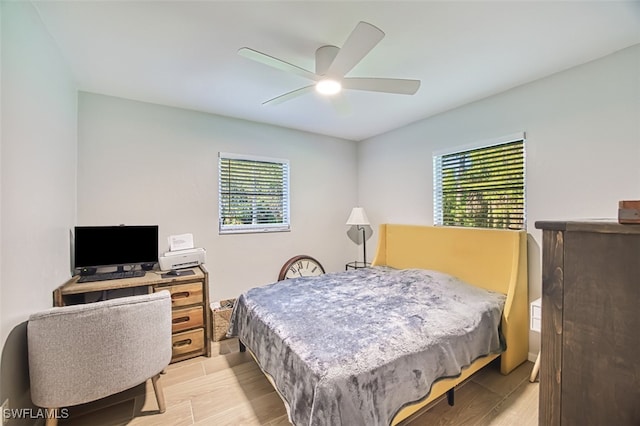 bedroom with ceiling fan, light wood-type flooring, and multiple windows