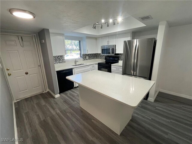 kitchen featuring a kitchen island, light countertops, black appliances, white cabinetry, and a sink