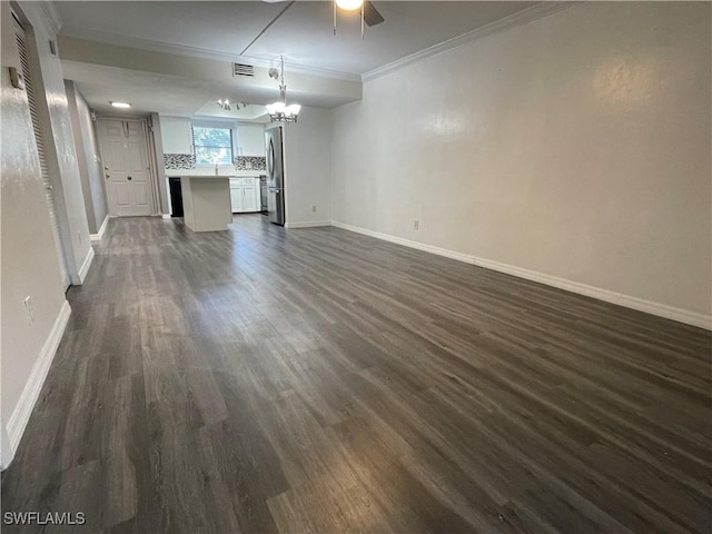 unfurnished living room with an inviting chandelier, baseboards, dark wood-type flooring, and crown molding