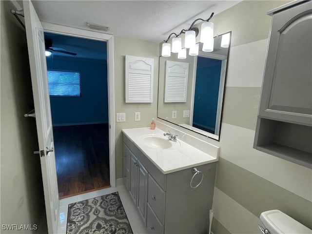 half bath featuring toilet, tile patterned floors, visible vents, and vanity