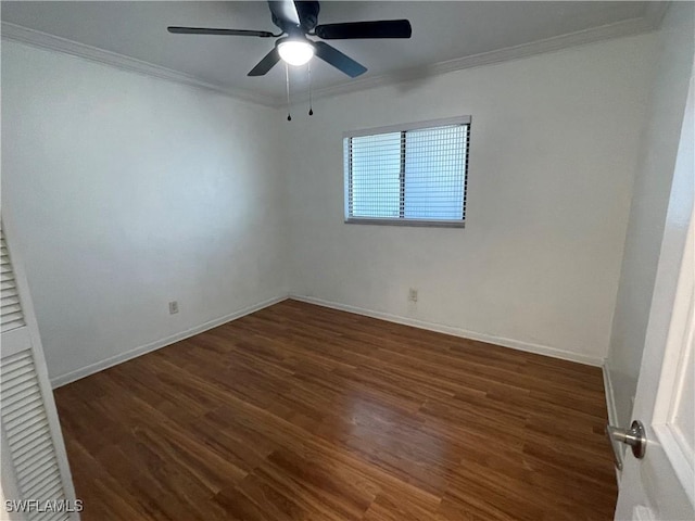 empty room featuring dark wood-style floors, crown molding, and baseboards