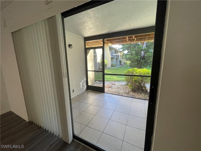 doorway to outside with a textured ceiling and tile patterned floors