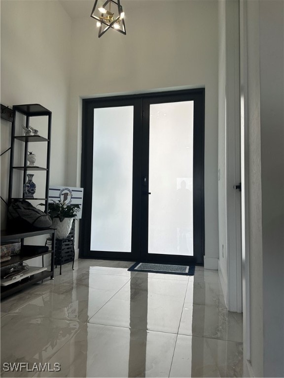 doorway featuring french doors, an inviting chandelier, a towering ceiling, and a wealth of natural light