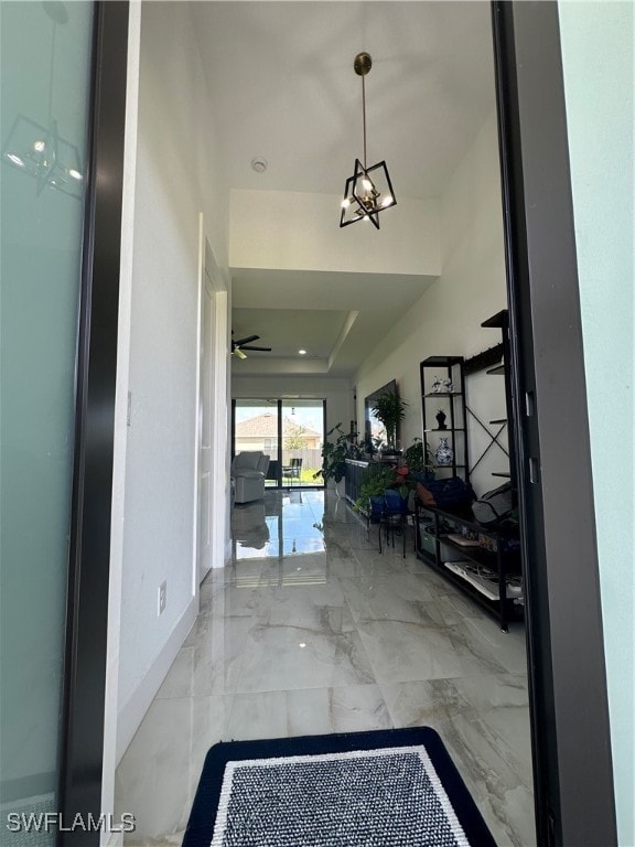 entryway with ceiling fan and a tray ceiling