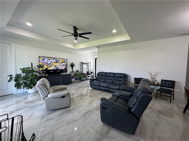 living room featuring ceiling fan and a raised ceiling