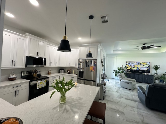 kitchen featuring ceiling fan, pendant lighting, white cabinetry, stainless steel appliances, and a kitchen bar