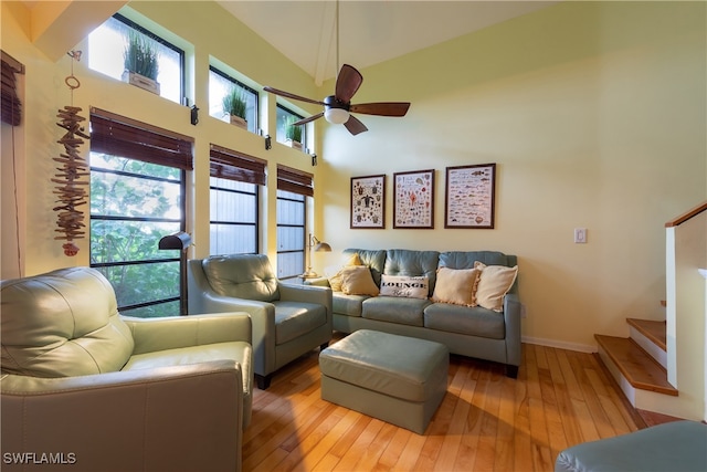 living room with a towering ceiling, ceiling fan, and light hardwood / wood-style flooring