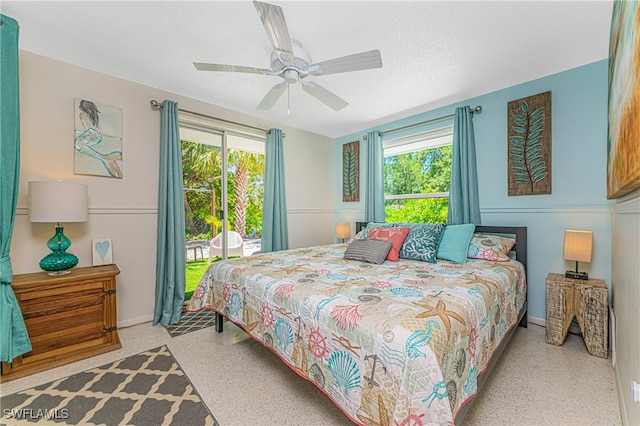 bedroom with ceiling fan, access to exterior, and a textured ceiling