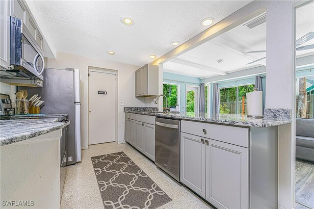 kitchen with ceiling fan, light stone counters, sink, gray cabinets, and stainless steel appliances